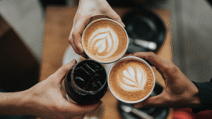 Zwei Personen stoßen mit Cappuccino-Tassen an